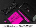 Blogging, recording or listening to podcasts, searching for jobs online, remote working, freelance concept. Phone, glasses, pen and a piece of paper with the words Audio podcast to indicate e-commerce