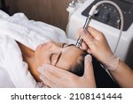 Small photo of Cosmetologist's hand is making cavitation rejuvenation skin treatment. Facial treatment. Facial skincare. Beauty skin care. Rejuvenation treatment.