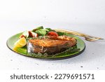 Aromatic baked salmon steak with juicy salad, tomatoes, lemon and fresh thyme on bright plate close up. Tasty and healthy food idea.