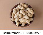 Fresh organic peanuts in the bowl on brown background