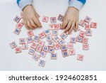 Small photo of Hands of child closeup holding wooden cubes with letters and alphabet on white background, concept of preparing for school, learning, development and fine motor skills, learning to read by syllables