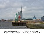 Small photo of Bremerhaven, Germany - August 18 2022: the historical lighthouse "Geestemole Nord", which has become unbalanced, seen in front of the Atlantic Hotel Sail City