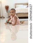 Small photo of Portrait of African happy little cute toddle baby infant kid playing toy while sitting on floor in home bedroom. Child with reflection on the floor, kid at home, happy childhood