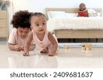 Small photo of Portrait of smiling African cute toddle baby infant kid crawling on floor with blurred background of curly hair brother boy play toy and father in bed. Happy family spending time together in bedroom.