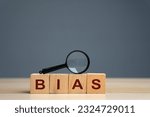 Small photo of Bias word on a wooden blocks. Prejudice. Personal opinions. Preconception. Concept of facts and biases. Magnifying glass