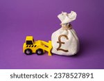 Small photo of A bulldozer pushes a british pound sterling moneфy bag. Ineffective use of funds. Money down the drain. Financing of dismantling works. Demolition services, land leveling. Industry machinery for rent.