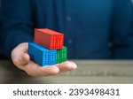 Small photo of A man holds shipping containers in his hand. Joint orders. Cost savings due to bulk purchases or shared shipping expenses. Retailers and Suppliers. Transport operators. Customs authorities.