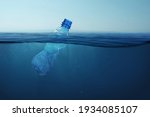 Garbage plastic bottle floats in blue sea water with underwater. Pollution of the environment and oceans. 
