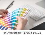 Graphic designer chooses colors from palette guide for painting and printing a new creative business work