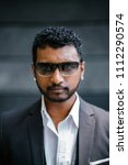 Small photo of Portrait of a handsome, roguish young Indian man in a 3-piece suit, white shirt and pocket square.