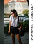 Small photo of Portrait of an unselfconscious, attractive and young Chinese Asian model girl smiling and goofing around as she poses for her photo on a street in Asia. She is tall, slim, cute and fashionable.