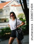 Small photo of Portrait of an unselfconscious, attractive and young Chinese Asian model girl smiling and goofing around as she poses for her photo on a street in Asia. She is tall, slim, cute and fashionable.