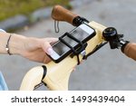 Woman hand uses the phone. The smartphone is attached to the bicycle steering wheel