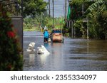 Small photo of Iloilo, Philippines - August 29, 2023: Super typhoon Goring or Saola brought flashfloods and rain to the country. Man pushing his pedicab as he wades in the flood.