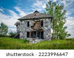 An abandoned stone house surrounded by trees on the Saskatchewan prairies outside Abernethy, SK