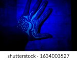 Small photo of A man's hand on a brick wall. Tattoo with a pattern on the arm using invisible ink. The tattoo glows under ultraviolet light.
