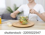 Asian woman eating salad on the dining table smiling and happy, Vegetable salads are rich in vitamins and minerals, Fat-low-calorie and high-fiber diets, Health care by eating fresh vegetables.