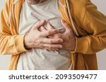 Small photo of Aching heart and heart attack, adult male with painful grimace pressing the upper abdomen with his hands to ease pain
