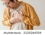 Small photo of Aching chest, adult male with painful grimace pressing the upper abdomen with his hands to ease pain, pericarditis concept