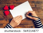 Woman writing love letter or romantic poem for Valentines day, top view of female hands