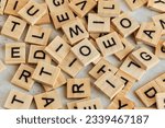 Pile of wooden tiles with various letters scattered on white stone like board, closeup view from above