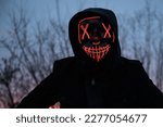 Small photo of Purge mask, halloween with pumpkin. LED mask, creepy scary man. Corona, Funny, October, outside. Urban scene car