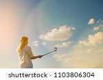 girl doing selfie on blue sky background. Woman holding a phone with Instagram IGTV.