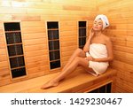 Young woman sitting on wooden bench in infrared sauna, space for text. Spa treatment