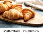 Board with tasty croissants on dark wooden table, closeup. French pastry