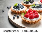 Different berry tarts on light table. Delicious pastries