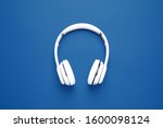 Headphones on bright background, top view. Color of the year 2020 (Classic blue)
