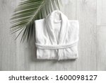 Flat lay composition with clean folded bathrobe on light wooden background