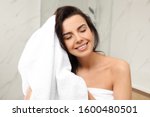 Young woman drying hair with towel in bathroom