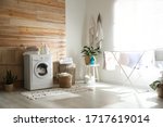 Stylish room interior with modern washing machine and drying rack
