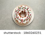 Traditional Christmas cake decorated with glaze, pomegranate seeds, cranberries and rosemary on light grey table, top view