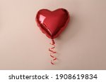 Red heart shaped balloon on beige background, top view. Saint Valentine's day celebration