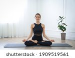 Young woman practicing lotus asana in yoga studio. Padmasana pose