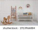 Small photo of Cute baby room interior with comfortable crib and wooden rocking horse