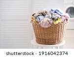 Wicker basket with dirty laundry indoors, space for text
