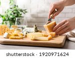 Woman cutting parmesan for cheese plate at table, closeup