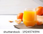 Glass of fresh tangerine juice on white table, space for text