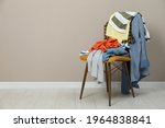 Different clothes on chair near light grey wall, space for text