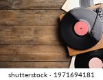 Modern player and vinyl records on wooden background, flat lay. Space for text