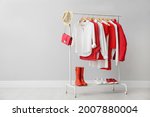 Rack with bright stylish clothes, shoes and accessories near light grey wall indoors, space for text