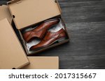 Stylish men's shoes and cardboard boxes on wooden floor, flat lay. Space for text