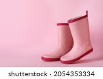 Pair of rubber boots on pink background, space for text