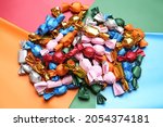 Many candies in different wrappers on color background, above view