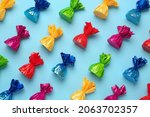 Candies in colorful wrappers on light blue background, flat lay