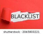 Small photo of Word Blacklist on white background through hole in red paper, top view