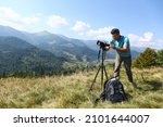 Photographer with backpack, camera and tripod surrounded by breathtakingly beautiful nature